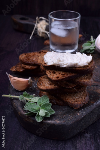 Rye bread toasts, lard paste and a misted glass of vodka on a black board. Ukrainian cuisine appetizer photo