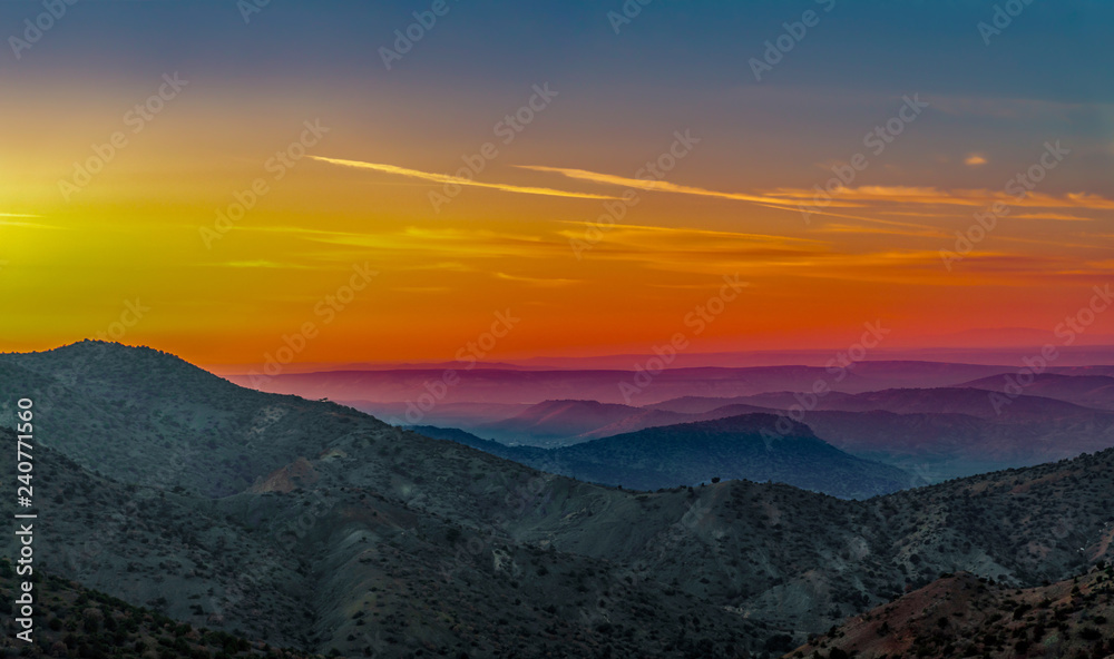 Landscape with orange and purple silhouettes of mountains, hills and forest