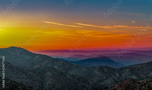 Landscape with orange and purple silhouettes of mountains, hills and forest