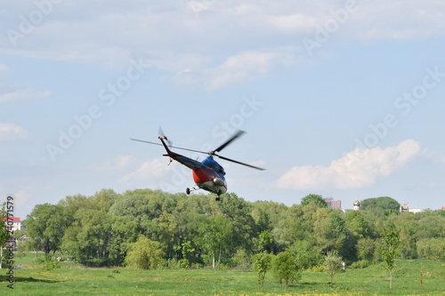 гражданский вертолет взлетает с поля в городе photo