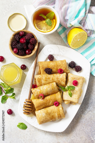 Healthy Pancakes breakfast. Stack of homemade thin pancakes or crepes whole grain flour, served with honey and fresh berries. Top view flat lay background.