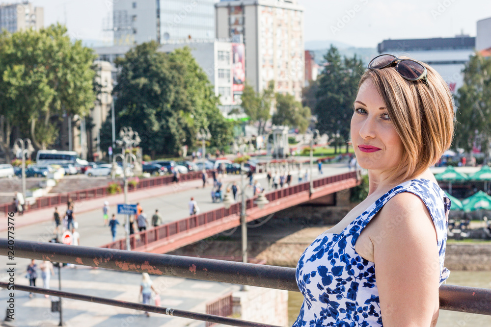 Beautiful Girl in a Blue Dress Smiling and Posing With Panoramic View of the City Center Behind Her