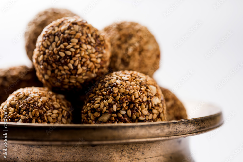 Tilgul Laddu or Til Gul balls for makar sankranti, it's a healthy food made using sesame, crushed peanuts and jaggery. served in a bowl. selective focus showing details. Tilgul Laddu or Til Gul balls for makar sankranti, it's a healthy food made using sesame, crushed peanuts and jaggery. served in a bowl. selective focus showing details.
