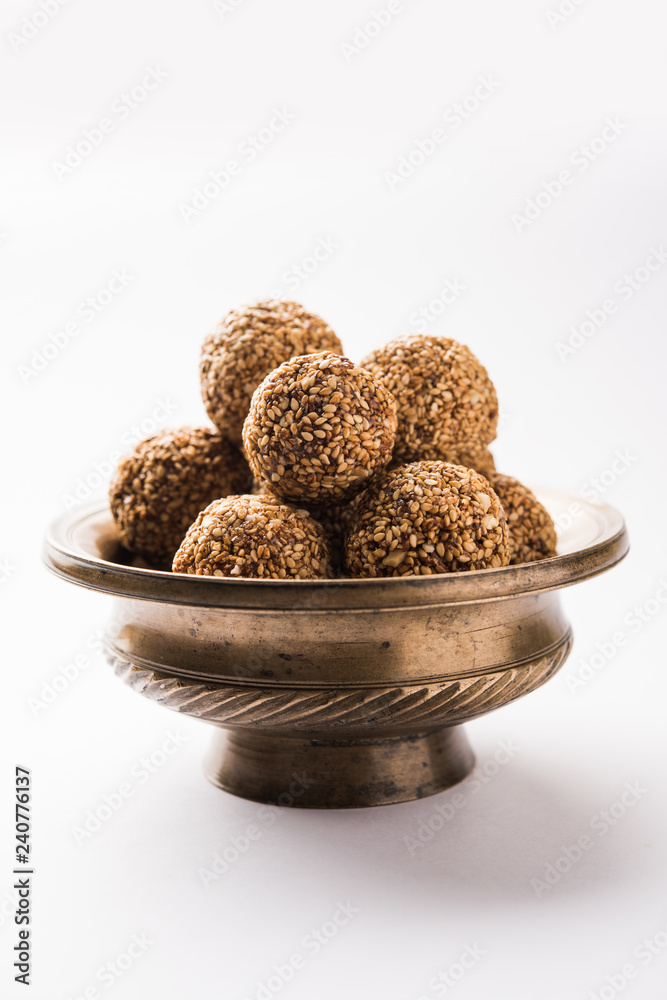 Tilgul Laddu or Til Gul balls for makar sankranti, it's a healthy food made using sesame, crushed peanuts and jaggery. served in a bowl. selective focus showing details. Tilgul Laddu or Til Gul balls for makar sankranti, it's a healthy food made using sesame, crushed peanuts and jaggery. served in a bowl. selective focus showing details.