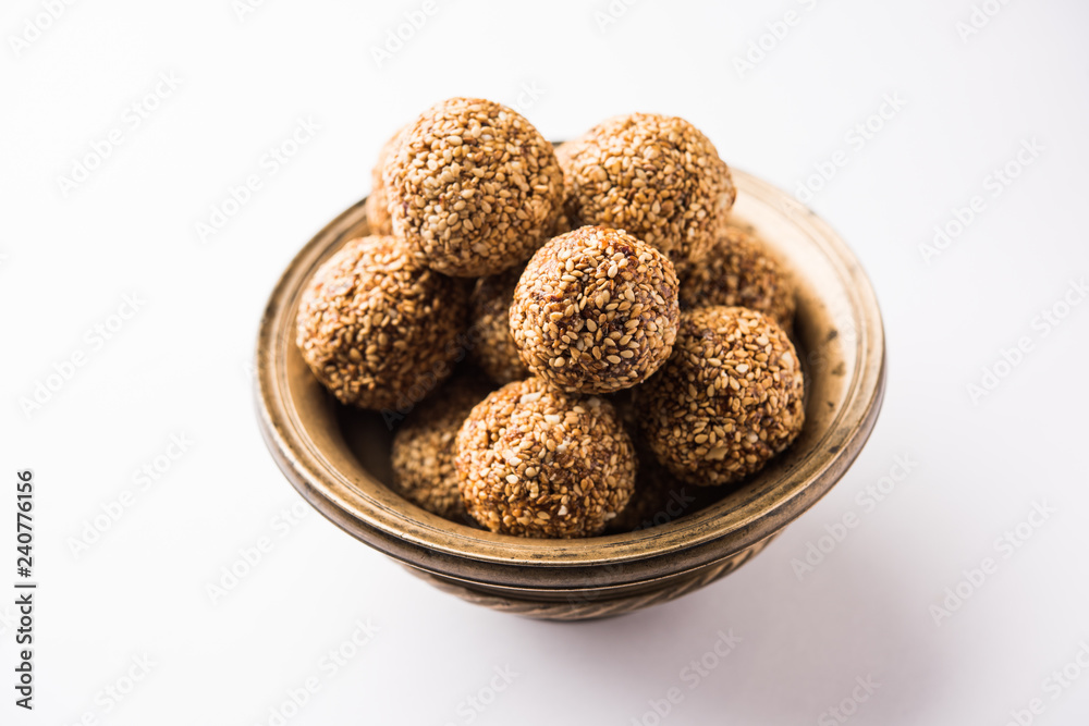 Tilgul Laddu or Til Gul balls for makar sankranti, it's a healthy food made using sesame, crushed peanuts and jaggery. served in a bowl. selective focus showing details. Tilgul Laddu or Til Gul balls for makar sankranti, it's a healthy food made using sesame, crushed peanuts and jaggery. served in a bowl. selective focus showing details.