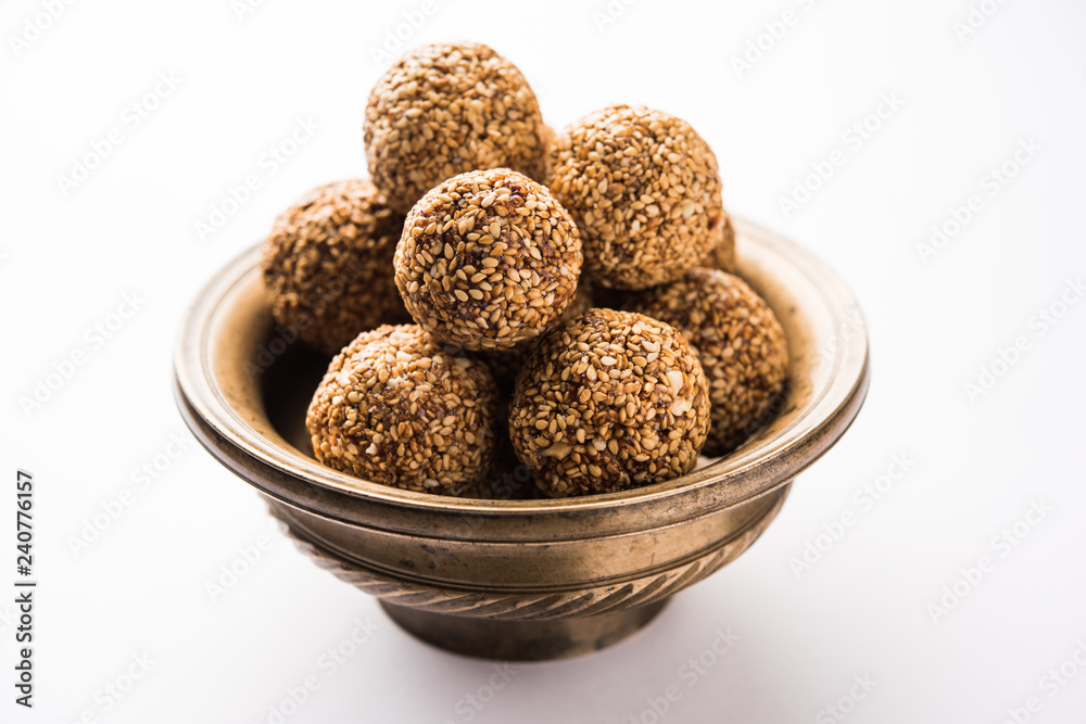 Tilgul Laddu or Til Gul balls for makar sankranti, it's a healthy food made using sesame, crushed peanuts and jaggery. served in a bowl. selective focus showing details. Tilgul Laddu or Til Gul balls for makar sankranti, it's a healthy food made using sesame, crushed peanuts and jaggery. served in a bowl. selective focus showing details.