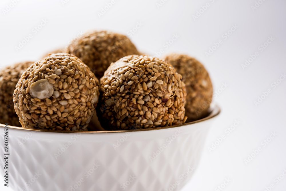Tilgul Laddu or Til Gul balls for makar sankranti, it's a healthy food made using sesame, crushed peanuts and jaggery. served in a bowl. selective focus showing details. Tilgul Laddu or Til Gul balls for makar sankranti, it's a healthy food made using sesame, crushed peanuts and jaggery. served in a bowl. selective focus showing details.