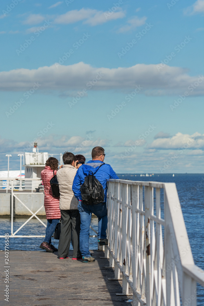 Tourists on the pier in Peterhof look at the Gulf of Finland. Russia