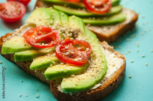 Fresh delicious toasts with sliced avocado, tomatoes and sesamum seeds. Healthy food concept.