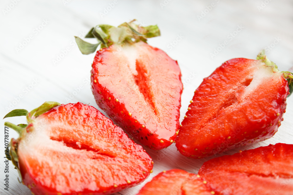 Sliced strawberries on white wooden background. Berry background with place for text. Selective focus.