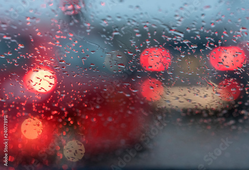 abstract pattern of colorful lights and rain drops during downpour on winshield of car