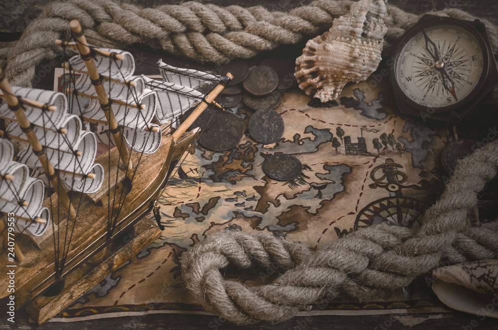 Pirate ship, treasure map, compass and a mooring rope on a wooden