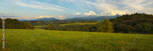 Panoramic view of Pyrenees with a green meadow on foreground at a sunset time