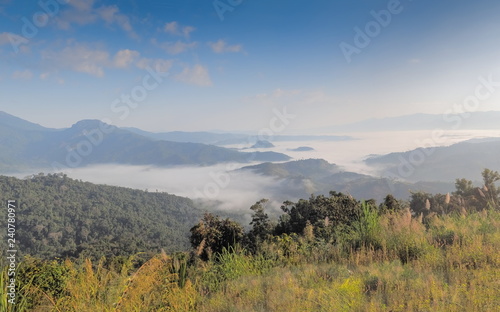 Mountain view morning of the hill around with the ocean of mist with blue sky background, sunrise at Tham Sakoen View Point attraction on route 1148, Tham Sakoen National Park, Nan Province, Thailand.