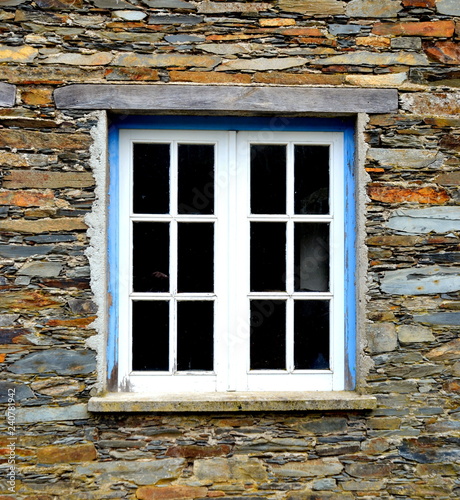 Rustic hand-hewn wood window set into a stone wall built from schist in Piodão, made of shale rocks stack, one of Portugal's schist villages in the Aldeias do Xisto.