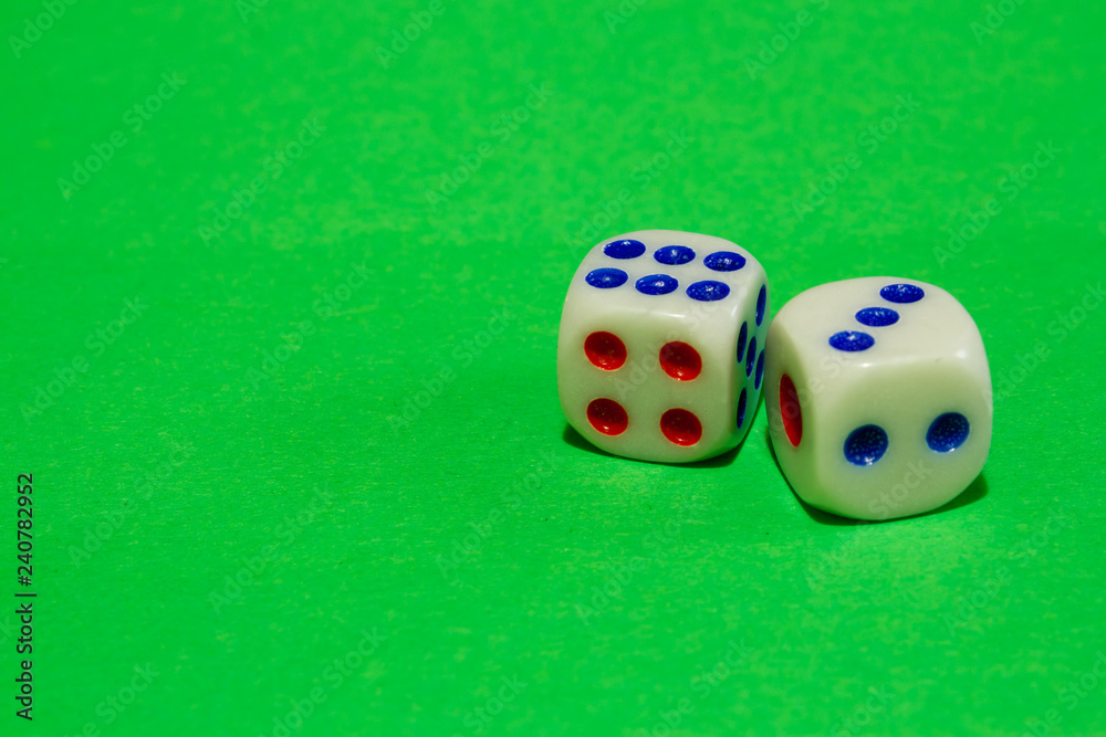 Two white dices with red and blue dots on green fabric material background. Casino gambling concept image Two white dices with red and blue dots on green fabric material background. Casino gambling concept image