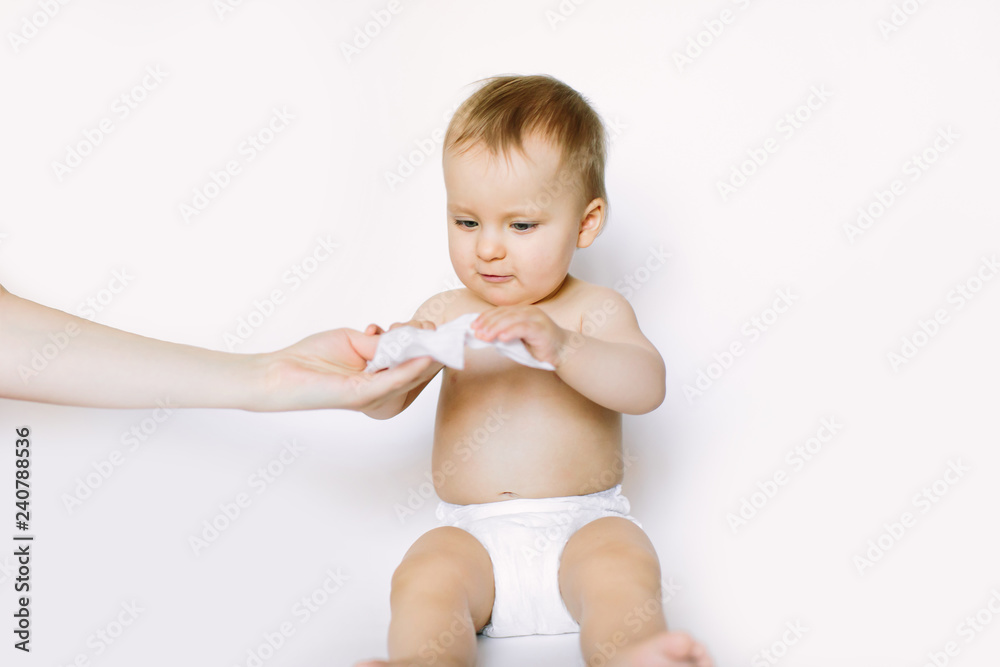 Hygiene - young momy wiping the baby skin with wet wipes. Little baby girl in diaper sitting and taking the wet wipe from mother hand. Cleaning wipe, pure, clean Hygiene - young momy wiping the baby skin with wet wipes. Little baby girl in diaper sitting and taking the wet wipe from mother hand. Cleaning wipe, pure, clean