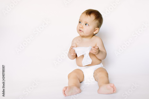 Tablou pe pânză Hygiene - little baby girl get wet wipes, and wipes her face isolated on white background