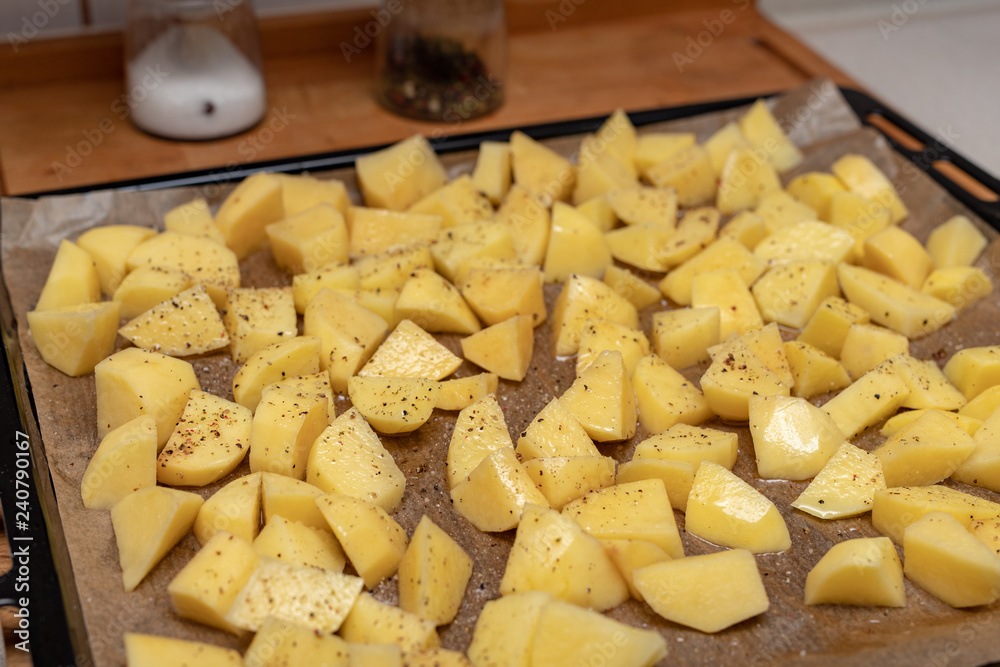 Raw potatoes sprinkled with spices. Vegetables cut into cubes prepared for baking. Raw potatoes sprinkled with spices. Vegetables cut into cubes prepared for baking.