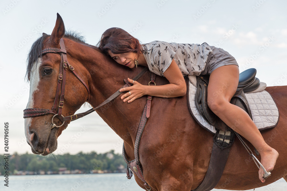 Obraz premium horse and young beautiful woman on river beach closeup