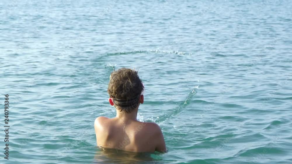 Back view of cute funny little kid shooting from toy water gun while swimming in warm blue summer sea during vacation. Real time 4k video footage. Back view of cute funny little kid shooting from toy water gun while swimming in warm blue summer sea during vacation. Real time 4k video footage.