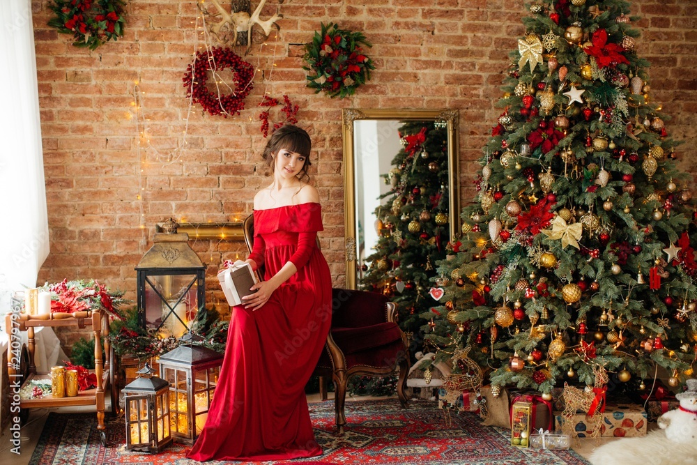 Portrait of beautiful young woman in red dress with makeup in Christmas decorations