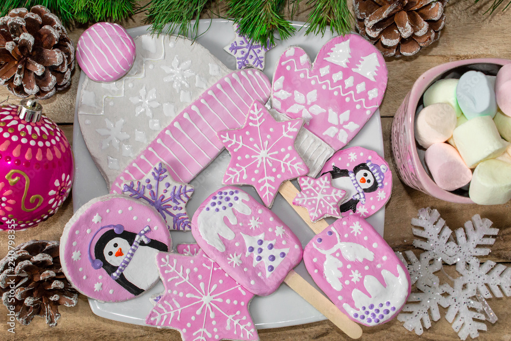New year preparations. Gingerbread, penguins, mittens and hats with asterisks and a mug of marshmallow on a wooden background. Branches of fir and ornaments. Festive Christmas background.
