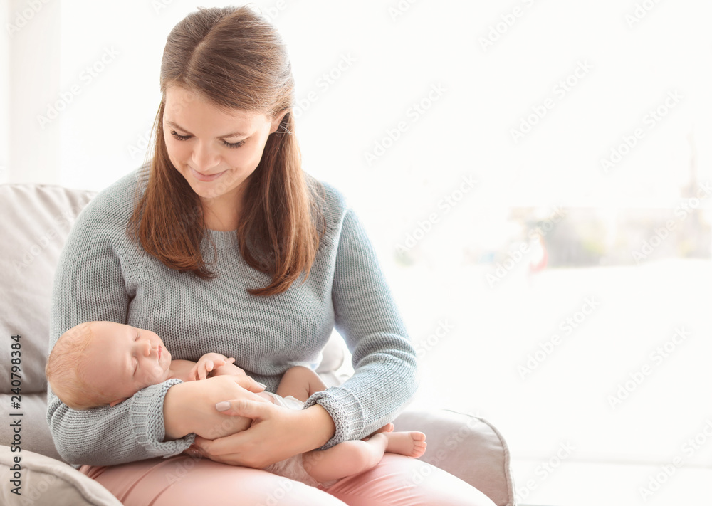 Young mother with her newborn baby in armchair at home Young mother with her newborn baby in armchair at home