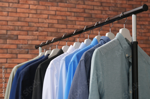 Wardrobe rack with stylish clothes near brick wall