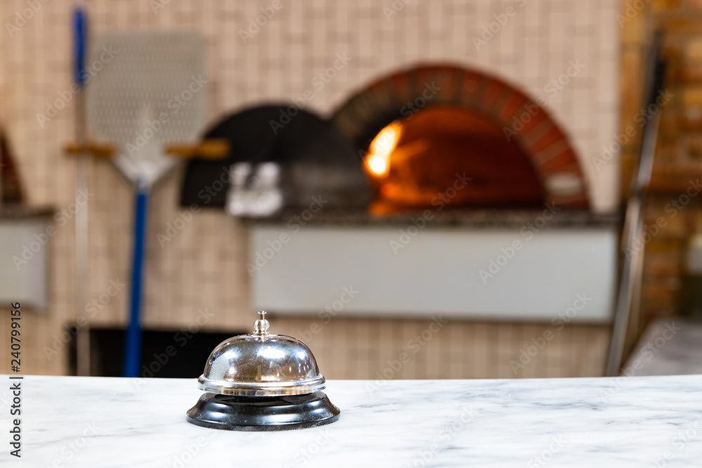 Pizzeria service bell close up wood fire oven in background Pizzeria service bell close up wood fire oven in background