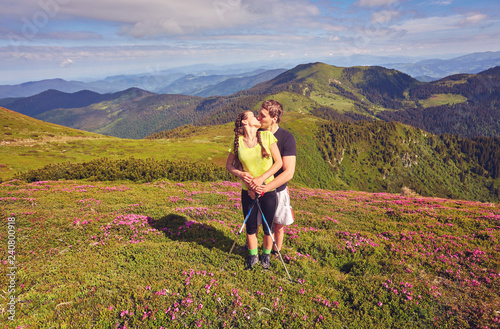 Man and woman standing and hugging on the top of the mountain, autumn hike with backpacks