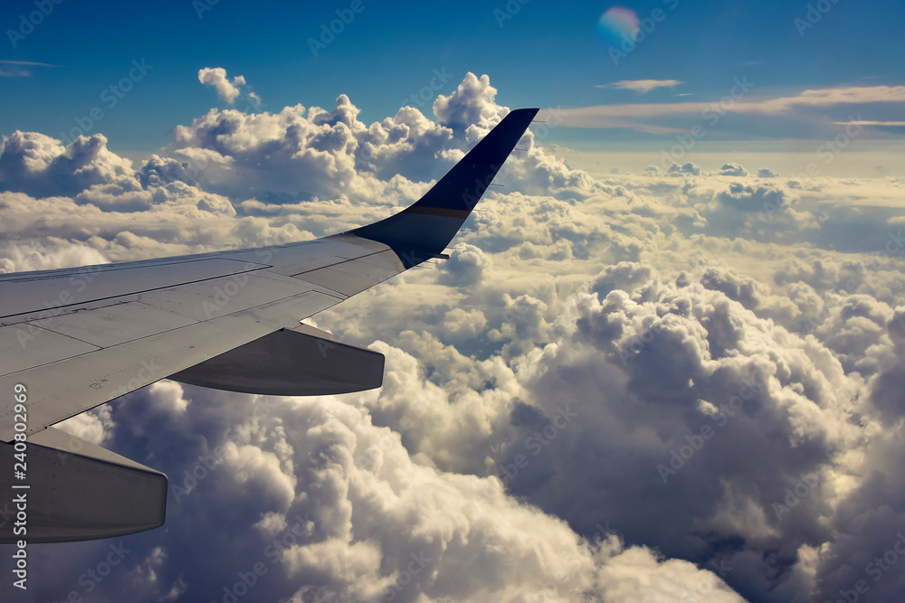 Obraz premium wing of an airplane flying above the clouds