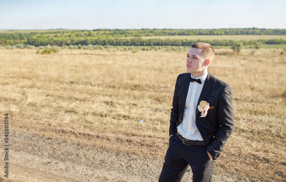 happy groom in black jacket standing in the field happy groom in black jacket standing in the field
