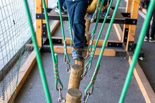 children walking on trunks suspended by ropes in an adventure park.