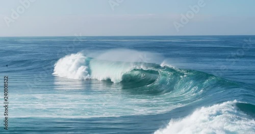 Aerial view of giant ocean waves crashing on sunny day 