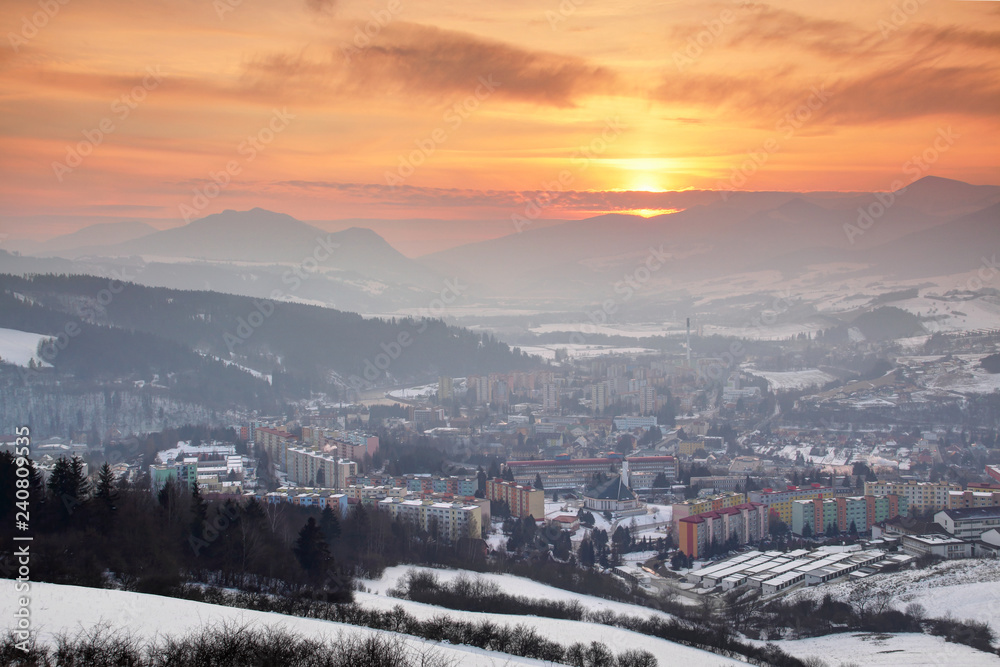 Glowing red sky and setting sun over Socialist era housing estates of snow covered town Dolny Kubin with Velka / Mala Fatra ranges, Carpathians Orava / Zilina regions Northern Slovakia Central Europe