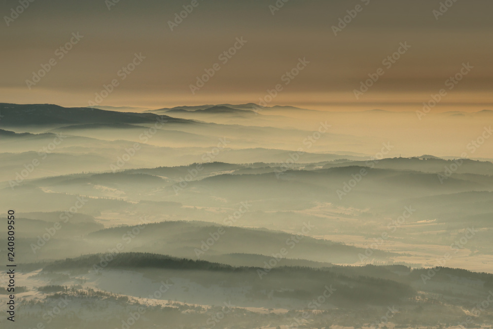 Aerial view of gentle slopes in winter haze at dawn in Gorce, Beskid Sadecki and Zywiecki ranges from Babia Gora peak, Beskidy Zachodnie mountains Western Carpathians Podhale Malopolska Poland Europe