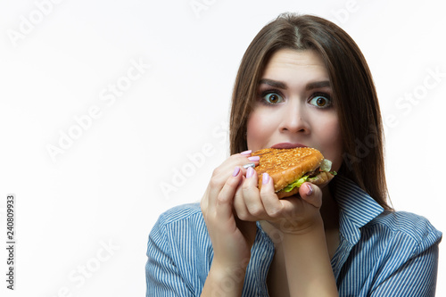 Unhealthy Eating Concepts. Caucasian Woman Eating Burger. Posing in Striped Shirt Indoors in Studio.