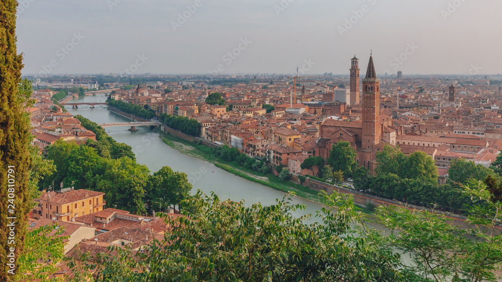 Adige river by the historical center of Verona, Italy, with the bell tower of the Church of Santa Anastasia and the Lamberti Tower