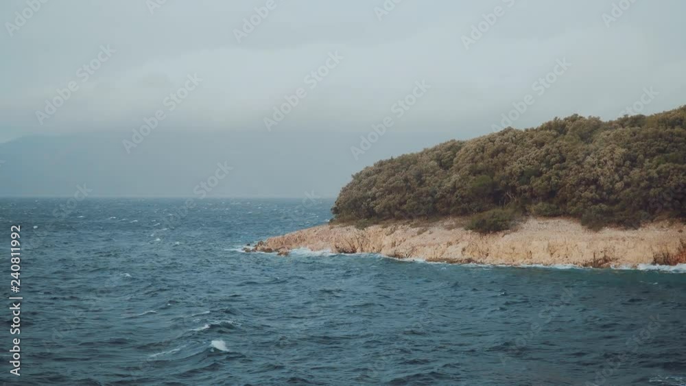 Adriatic sea in the fall. Waves are sweeping the shore of Croatian island. Windy weather. Shot from a ferry. Adriatic sea in the fall. Waves are sweeping the shore of Croatian island. Windy weather. Shot from a ferry.