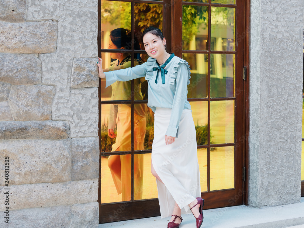 Portrait of beautiful Chinese girl standing in front of glass door and posing with her shadows in mirror in sunny afternoon, beauty, emotion, expression and people lifestyle concept. Portrait of beautiful Chinese girl standing in front of glass door and posing with her shadows in mirror in sunny afternoon, beauty, emotion, expression and people lifestyle concept.