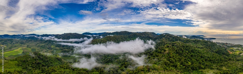 Aerial panorama of mist and fog over a tropical rainforest at sunset