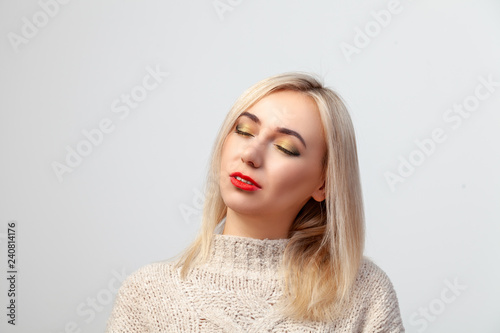 Portrait of a sexy blonde with closed eyes and makeup in the oriental style: bright golden brown shade and red lipstick on the lips, mouth sensually parted on a white background in the studio visage.