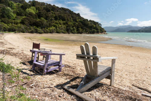 Three old, wooden seats on the beach at Kenepuru Sound, Marlborough Sounds, New Zealand.