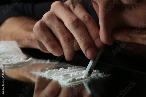 Drug addict taking cocaine at table, closeup view photo