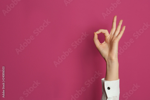 Young woman showing OK gesture on color background. Space for text photo