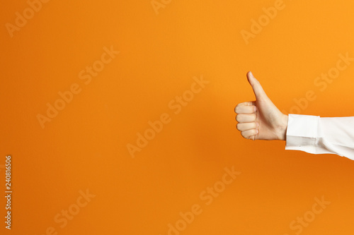 Young woman showing thumb sign on color background. Space for text photo