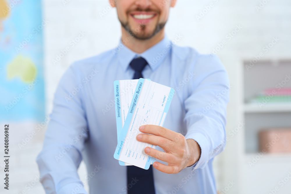 Male consultant holding tickets in travel agency, closeup Male consultant holding tickets in travel agency, closeup