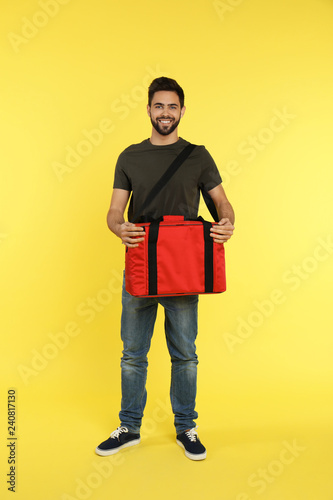 Young courier with thermo bag on color background. Food delivery service © New Africa
