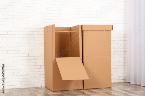 Empty cardboard wardrobe boxes against brick wall indoors © New Africa